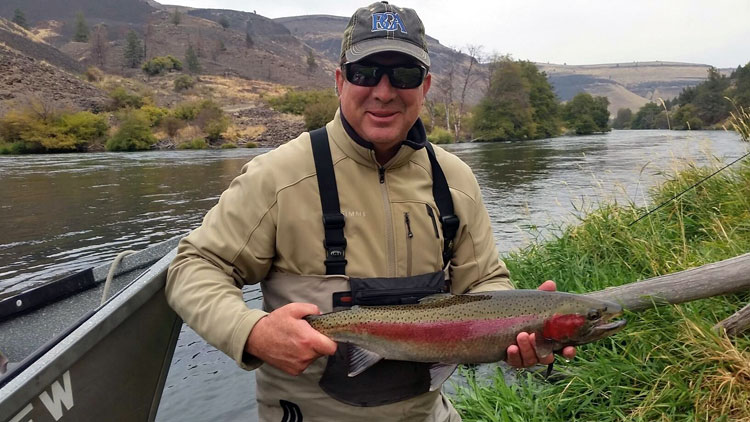 A client with a steelhead caught on a nymph